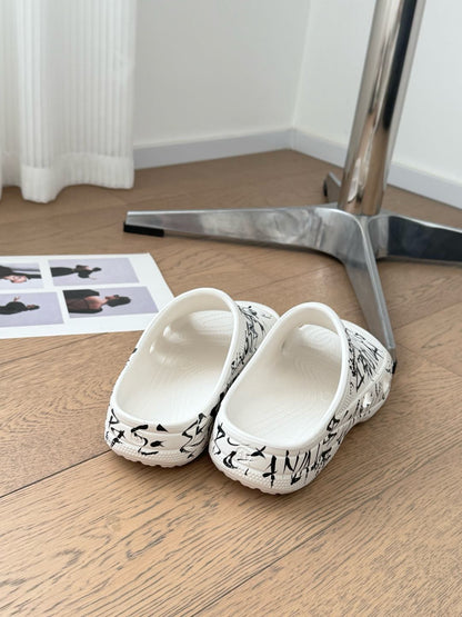 POOL GRAFFITI CROCS SLIDE SANDALS IN WHITE AND BLACK RUBBER