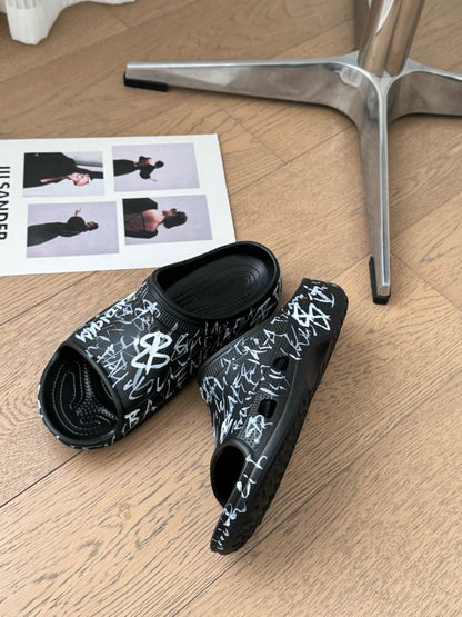 POOL GRAFFITI CROCS SLIDE SANDALS IN BLACK AND WHITE RUBBER