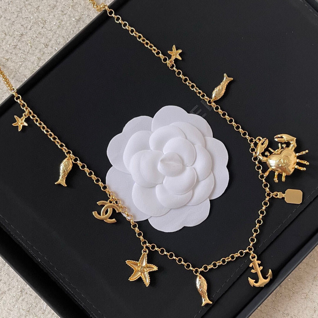 MULTI-CHARM CHAIN BELT IN GOLD METAL CRYSTAL DOUBLE C PENDANT AND OCEAN MOTIFS